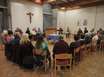 Gebet für die Einheit der Christen Menschen sitzen im Stuhlkreis in einem Gemeindesaal und beten und singen gemeinsam. In der Mitte steht ein geschmückter Tisch mit einer Kerze